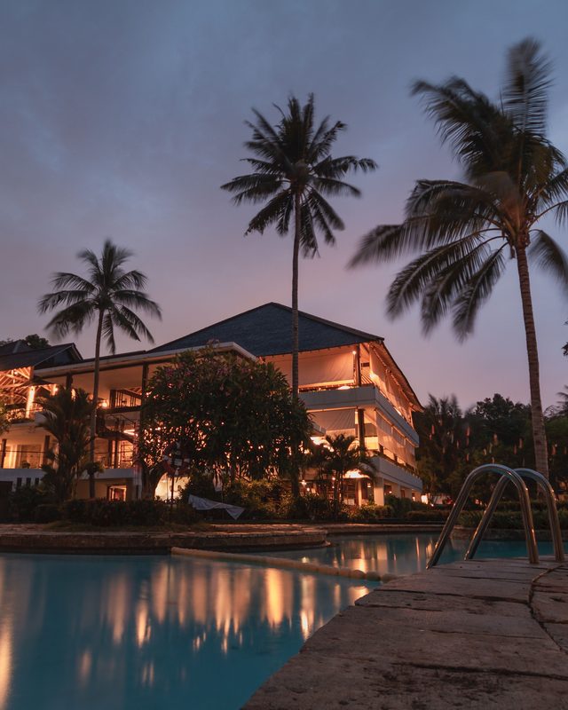Resort and pool lit at dusk with palm trees